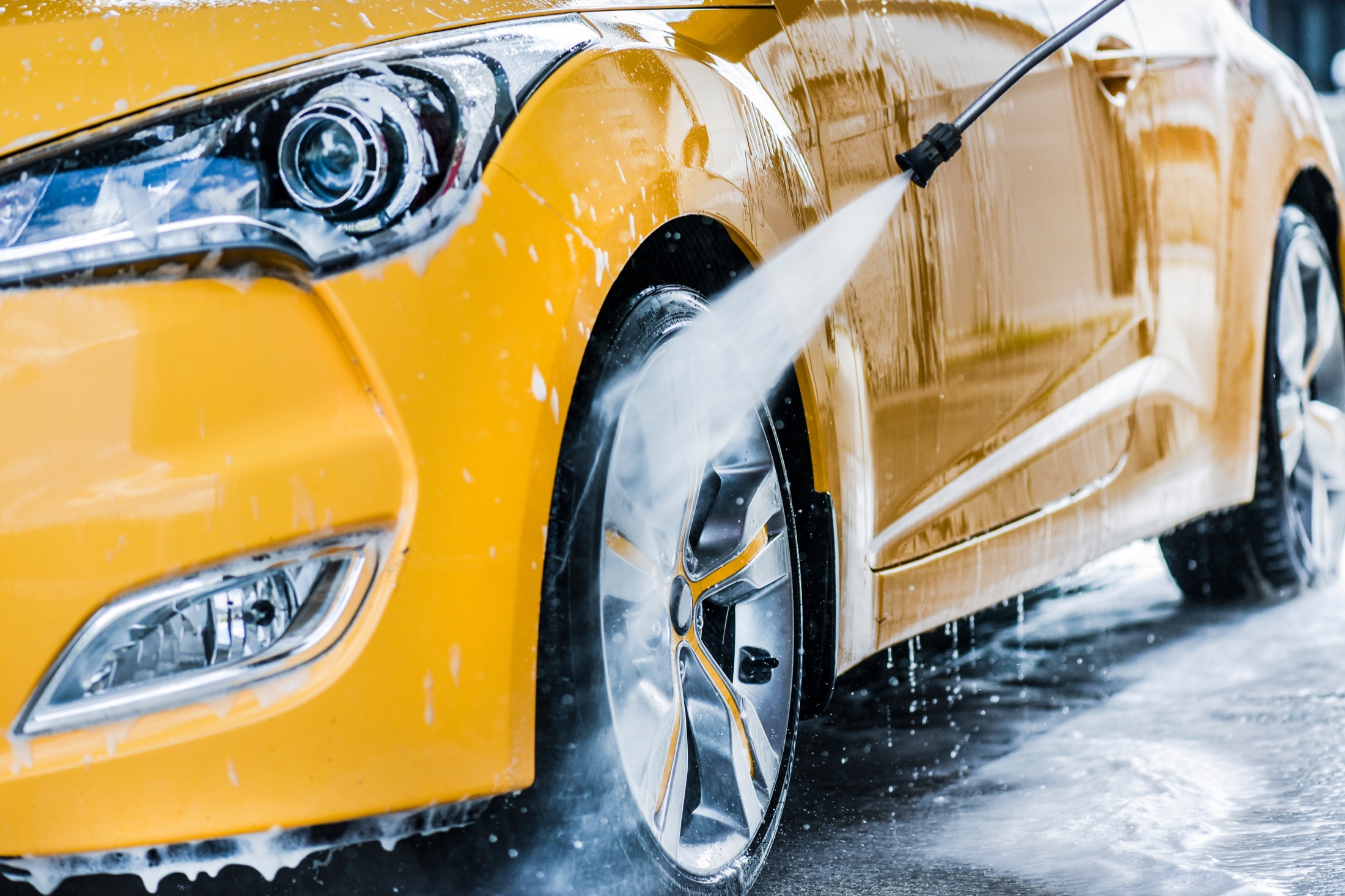 Customer using a pressure washer to clean a car